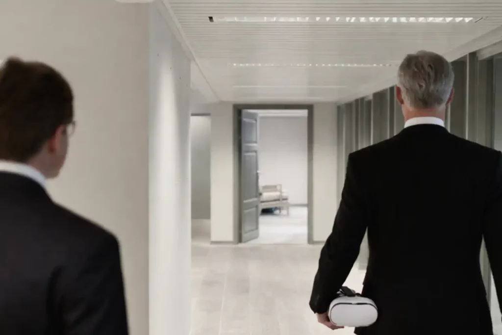 Deux personnes marchant dans un couloir professionnel, dont une tenant un casque de réalité virtuelle pour une expérience de recrutement immersive